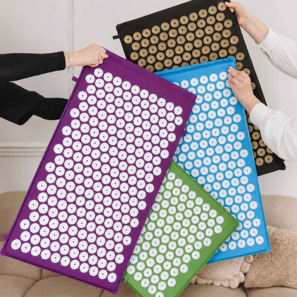 Différentes couleurs de tapis d’acupression présentées côte à côte.